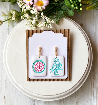 White rectangular statement earrings with a blue bird and colorful circular tile motif