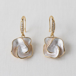 Mother-of-pearl camellia flower dangle earrings - front view on white linen background