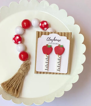 Handmade polymer clay teacher earrings with red apples, green leaves, and cream ruler dangles with black markings