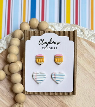 Polymer clay teacher stud earrings with yellow pencils, pink erasers, and white notebook-paper hearts with blue lines and red margins