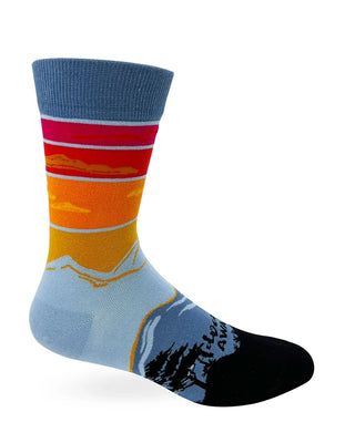 Side view of men's Adventure Awaits sock with blue-gray cuff, warm sunset bands, blue mountain scenery, and black toe