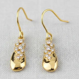 Gold teardrop and crystal row drop earrings - front view on linen background
