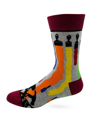 Side view of gray Dad crew sock with colorful paint streaks beneath paintbrushes, tool motifs, and burgundy cuff, heel, and toe