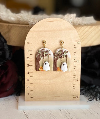 Halloween ghost earrings featuring a white ghost on a swing beneath a woodland tree