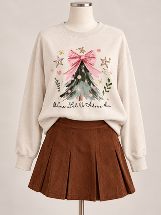 Cream Christmas sweatshirt with a green tree, pink bow, stars, and Oh Come Let Us Adore Him lettering, styled with a brown skirt