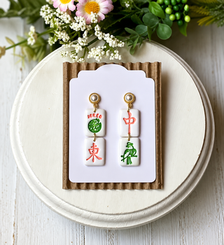 White double-tile statement earrings with a Joker design, red and pink details, and a green bird motif