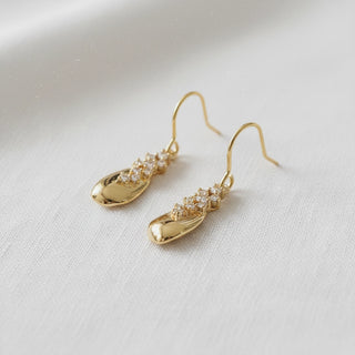 Gold teardrop and crystal row drop earrings - angled side view on white background