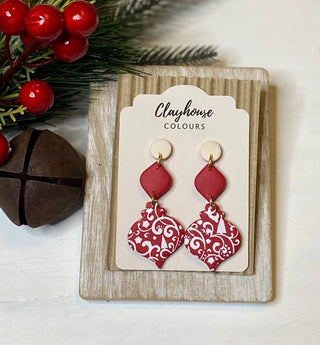 Handmade red-and-white patterned polymer clay holiday statement earrings on a festive jewelry card