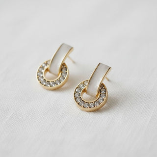 White enamel bar and crystal pavé horseshoe drop earrings gold tone - angled side view on white linen
