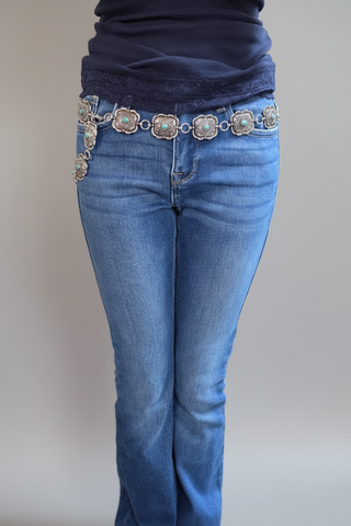 Western silver carved rectangle concho belt with turquoise stones worn on medium wash blue denim jeans